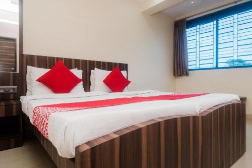a large bed with red pillows in a room at Hotel O Shalimar in Mumbai