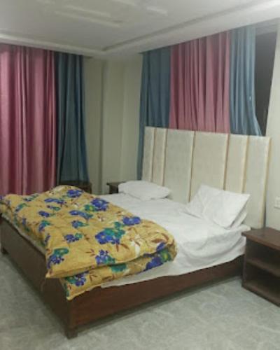 a bedroom with a bed with a yellow blanket on it at Kings Inn Hotel in Dargai