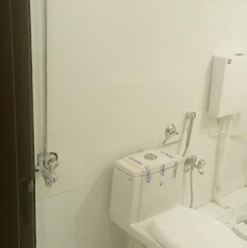 a white bathroom with a toilet and a sink at Kings Inn Hotel in Dargai