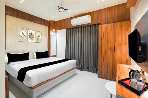 a bedroom with a bed and a flat screen tv at Super Townhouse GIDC Bol Sanand in Ahmedabad