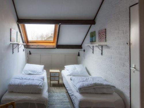 two beds in a small room with a window at Vakantiehuis in Stavenisse