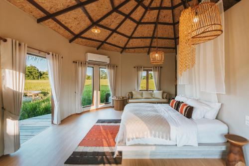 a bedroom with a bed and a large window at Na Bua Villa Chiangrai in Ban Rim Lao