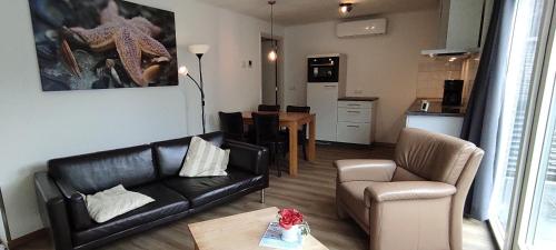 a living room with a black leather couch and a chair at Stuivezandeweg 6 in Callantsoog