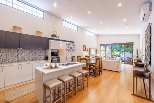 a kitchen with white cabinets and a kitchen island with bar stools at 6A Hough Street - Sophisticated pet friendly home with air con, wi-fi and linen provided in Nelson Bay