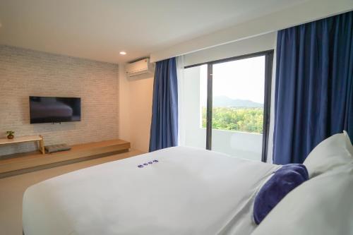 a bedroom with a large bed and a large window at Kokotel Rayong Beachfront in Ban Pak Khlong Phe