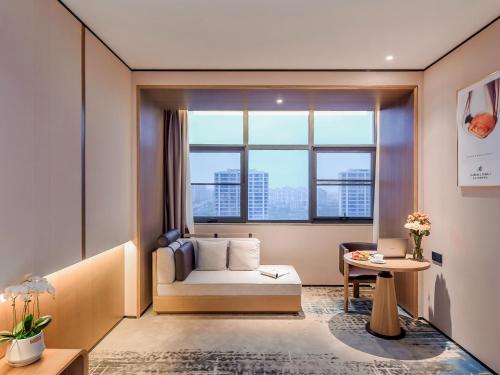 a living room with a couch and a large window at Mousse Hotel Liyang Railway Station Museum Branch 