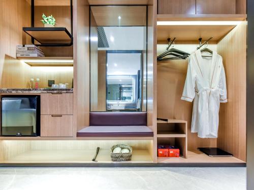 a dressing room with a white robe and a mirror at Mousse Hotel Liyang Railway Station Museum Branch 