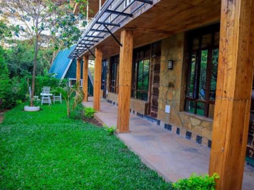 eine Veranda eines Hauses mit Holzpfosten und grünem Gras in der Unterkunft Ankara Garden Resort Nairobi in Ongata Rongai 