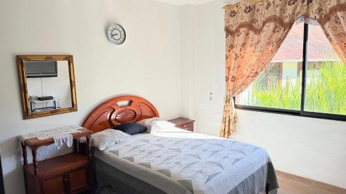 a bedroom with a bed and a mirror and a window at Villa Mariaclaudia completa in Macas