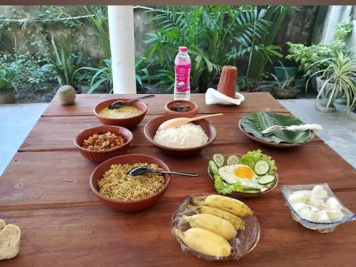 Una mesa de madera con cuencos de comida encima. en Sihe House, en Gintota