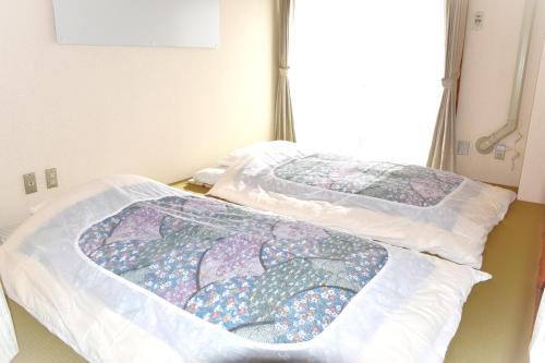 two beds in a hospital room with a quilt at cotomaro 305 -Apartment Stay Near Matsumoto Castle- in Matsumoto