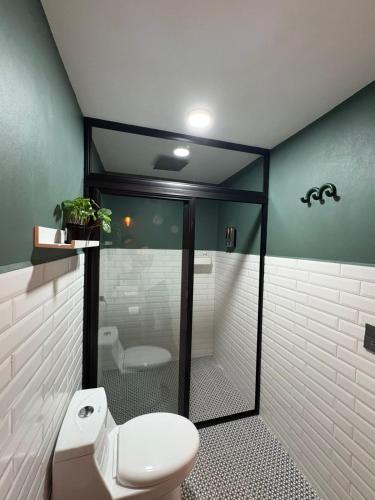a bathroom with a toilet and a glass shower at Loft ËNXË Boutique Habitación Olivo in Cuetzalán del Progreso