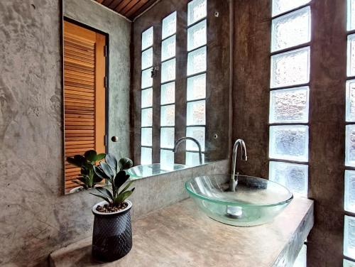 a bathroom with a bowl sink and a window at Phakphing Erawan Homestay - พักพิง เอราวัณ โฮมสเตย์ in Tha Kradan