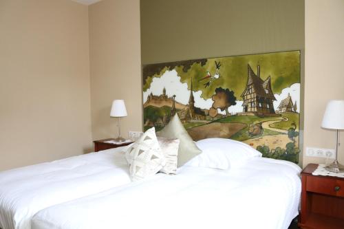 a bedroom with a white bed with a painting on the wall at Auberge Le Meisenberg in Châtenois