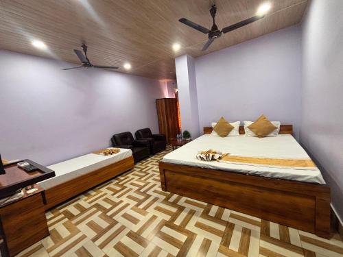 a room with two beds and a chair in it at Collection O Arya Vidyapeeth College Guwahati in Guwahati