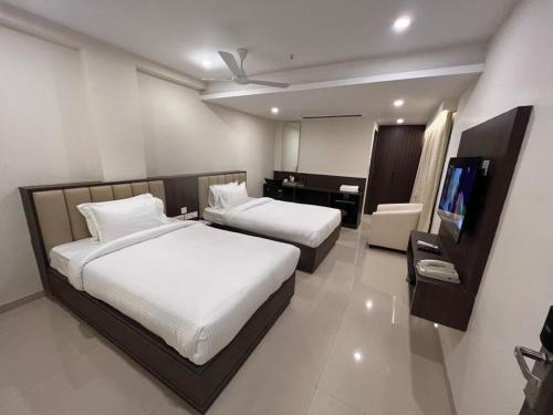 a bedroom with two beds and a flat screen tv at Townhouse Vizianagaram Formerly Happy Stays in Vizianagram City