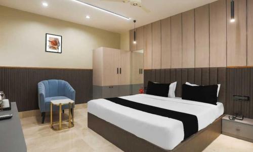 a bedroom with a large bed and a blue chair at Townhouse Oak CSJMU Kanpur Formerly Shree Dev Villa in Kaliānpur