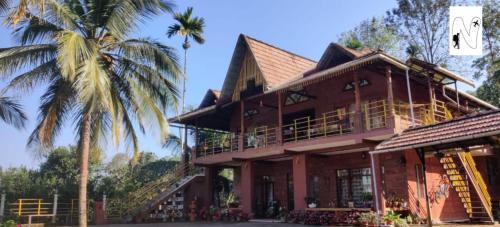 ein Haus mit einer Palme davor in der Unterkunft Coffee Voyages in Madikeri