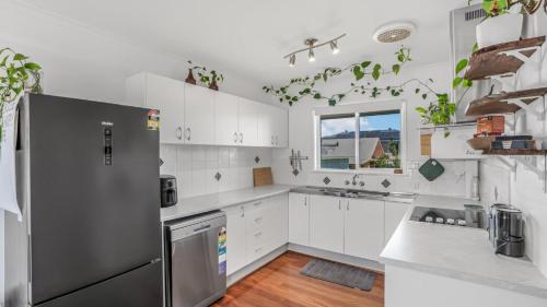 une cuisine avec des armoires blanches et un réfrigérateur en acier inoxydable dans l'établissement The Infinite Pi Escape, à Bongaree