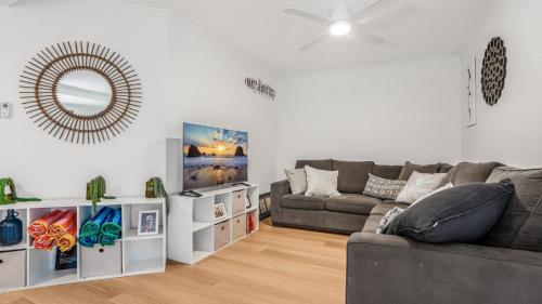 un salon avec un canapé et un miroir dans l'établissement The Infinite Pi Escape, à Bongaree