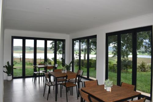 Un comedor con mesas y sillas y grandes ventanales. en Mable's BnB, 