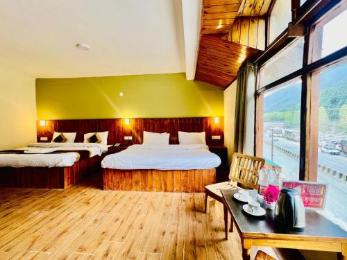 マナリにあるHotel Fast Way Manali #Near zingbus #Near Pizzahut #By silverlandのベッド2台とテーブルがあるホテルの部屋