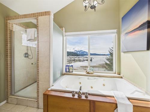 a bathroom with a bath tub and a window at Juneau Oceanfront Home Overlooking Auke Bay in Mendenhaven