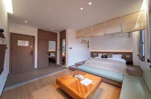 a bedroom with a large bed and a wooden table at Xiamen Bashi Living Room B&B 厦门八适客厅民宿 in Xiamen