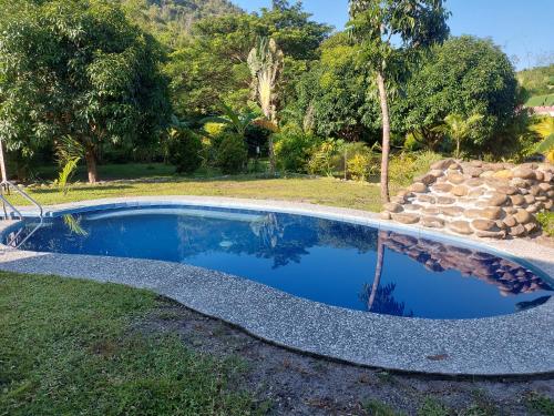 a swimming pool in a yard with a stone wall at Mountain Side Travellers Inn in Zambales