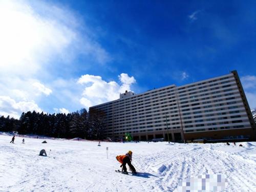a person skiing in the snow in front of a building at 47 - Snow Village Cozy Lodge Yuzawa in Yuzawa