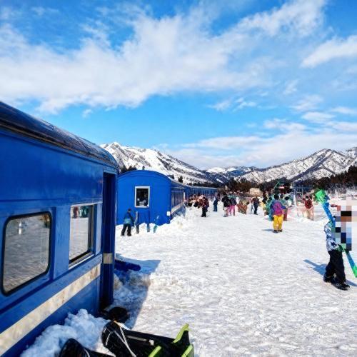 a group of people standing in the snow next to a train at 47 - Snow Village Cozy Lodge Yuzawa in Yuzawa