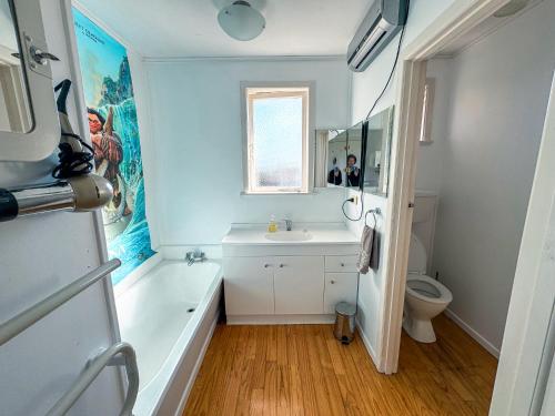 a bathroom with a tub and a sink and a toilet at Mid-Century Peace in a Prime Location in Auckland