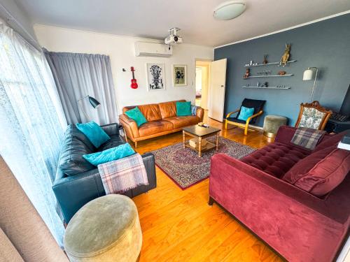 a living room with two couches and a table at Mid-Century Peace in a Prime Location in Auckland