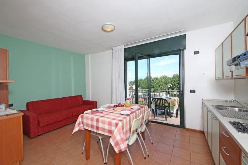 a kitchen and living room with a table and a red couch at Nettuno Residence Hotel in Peschiera del Garda