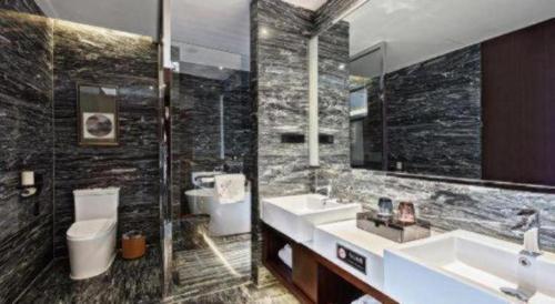 a bathroom with two sinks and a toilet and a mirror at Ramada by Wyndham Wuhan Dongxihu in Wuhan