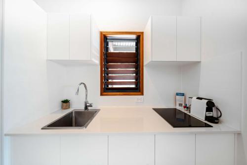 a white kitchen with a sink and a window at Latitude 17 - Suite 3 in South Mission Beach