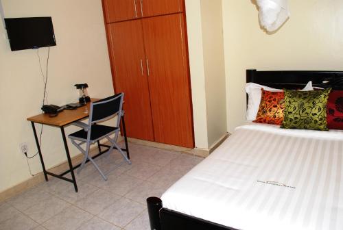 Schlafzimmer mit einem Bett und einem Schreibtisch mit einem Telefon in der Unterkunft Dich Comfort Hotel - Main Branch in Gulu