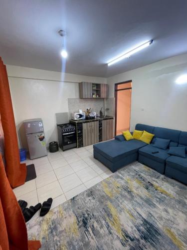 a living room with a blue couch and a kitchen at Kings 1 Bedroom in Busia