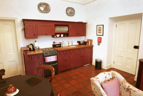 a kitchen with red cabinets and a table and a stove at Triumphal Arch Lodge in Creagh