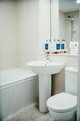 a white bathroom with a sink and a toilet at Urban Elegance: Luxury; Sleeps 6 in Belfast