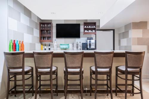 a kitchen with a bar with four stools at Ramada by Wyndham Minneapolis Golden Valley in Minneapolis