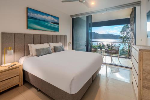 a bedroom with a large bed and a balcony at Edge 2 - Oceanfront Luxurious and Spacious 4 Bedroom Split Level Apartment with buggy and valet service in Hamilton Island