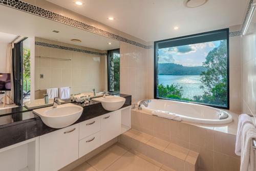 a bathroom with two sinks and a large window at Edge 2 - Oceanfront Luxurious and Spacious 4 Bedroom Split Level Apartment with buggy and valet service in Hamilton Island