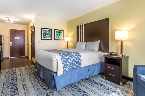 una habitación de hotel con una cama grande y una silla azul en Suburban Studios Donaldsonville - Gonzales, en Donaldsonville