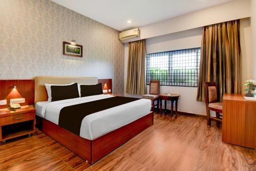une chambre d'hôtel avec un grand lit et un bureau dans l'établissement Super Townhouse Oak Sri Mahadeshwara Convention Centre Formerly Shri Aprameya Resort, à Hārohalli