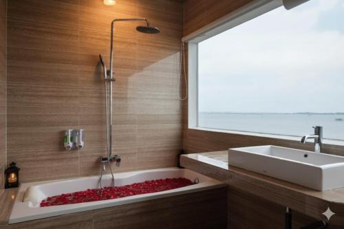 a bathroom with a tub and a sink and a window at D'Season Premiere Hotel in Kesembu