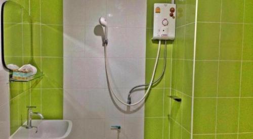 a shower in a green and white bathroom with a sink at The Pride Hotel At Laemsing in Ban Pak Nam