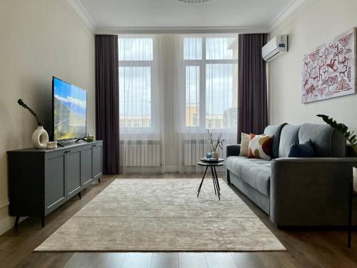 una sala de estar con un sofá y un televisor en Экспо апарт 176, en Astana