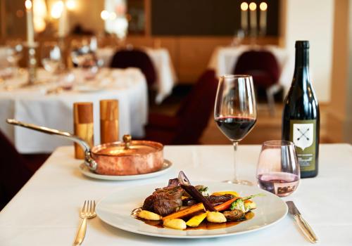 a table with a plate of food and a bottle of wine at Bellevue Parkhotel & Spa - Relais & Châteaux in Adelboden