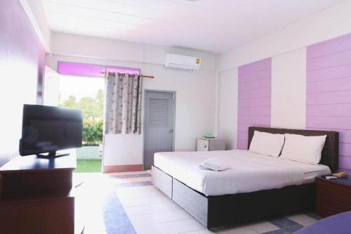 Un dormitorio con una cama y un televisor. en Kumkaew Udon, en Udon Thani